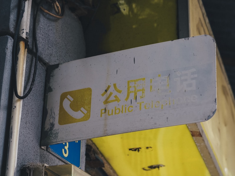 一个人站在家门口，手里拿着手机，正在拨打附近开锁店电话，表情焦急