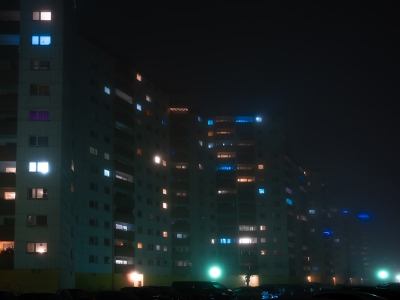 一个人站在家门口，手里拿着手机，表情焦急，背景是夜晚的住宅区